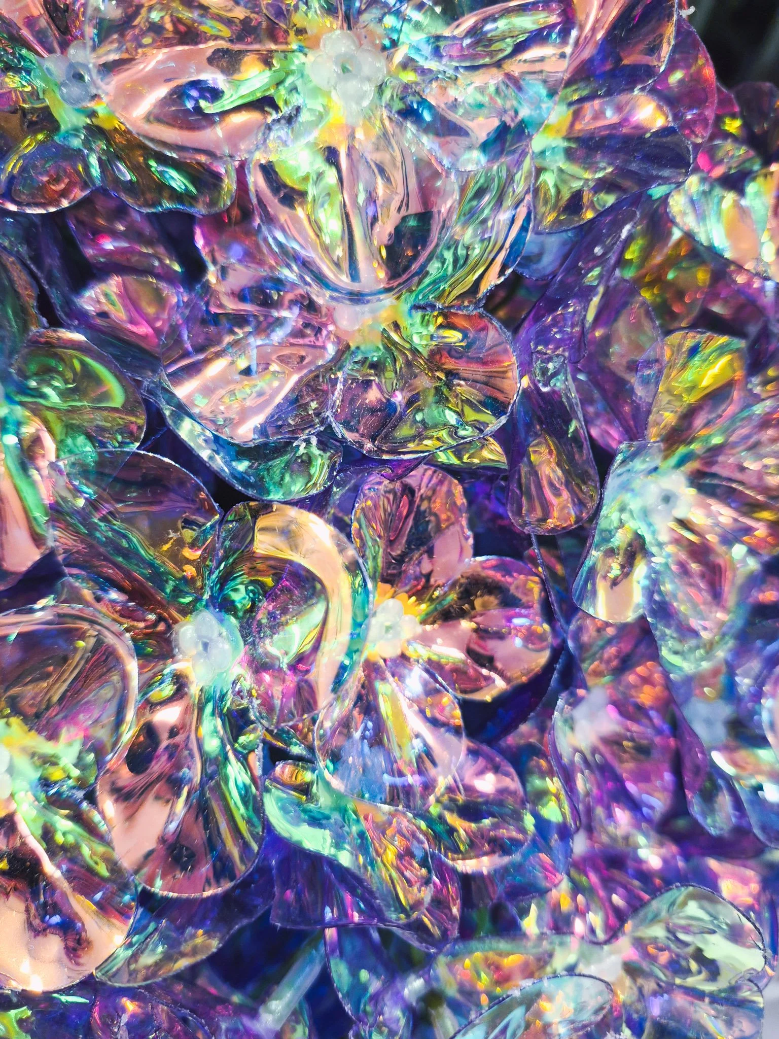 Close-up of iridescent glass flower decorations reflecting rainbow colors and light