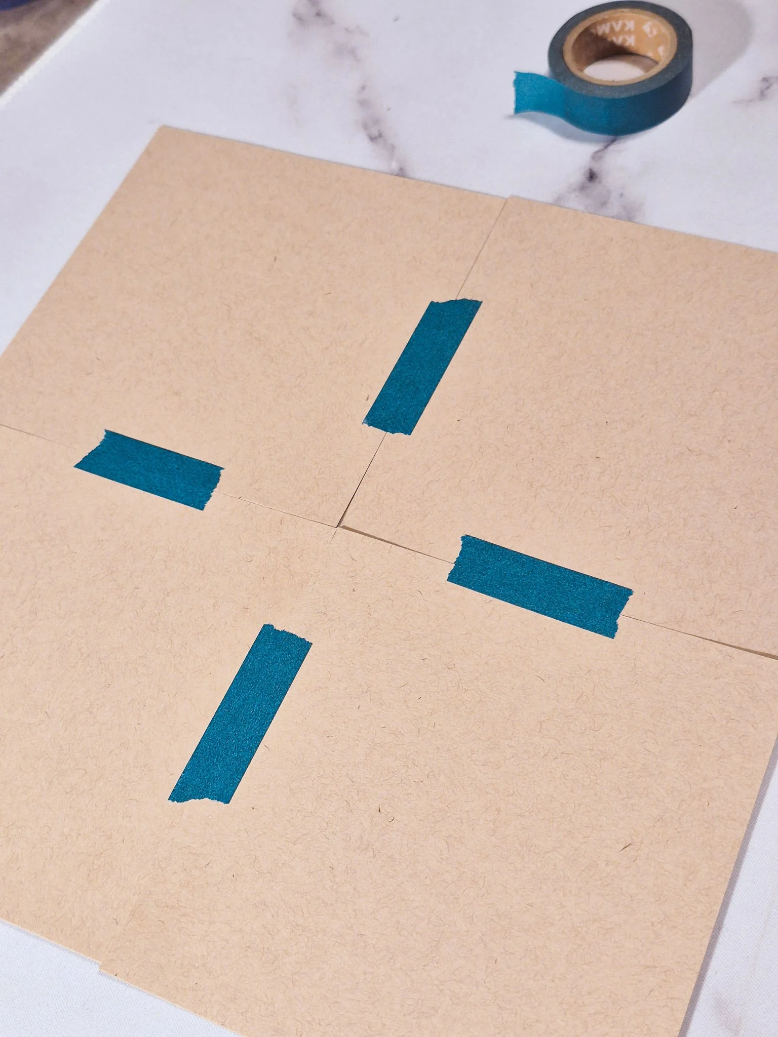 Four square papers lightly taped together on the back to form a single working canvas for a repeat pattern