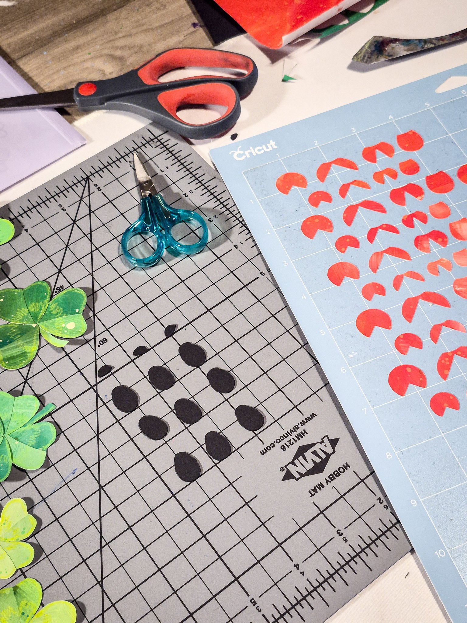 Workspace showing cut paper collage elements, scissors, and tools used in creating an analog repeat pattern