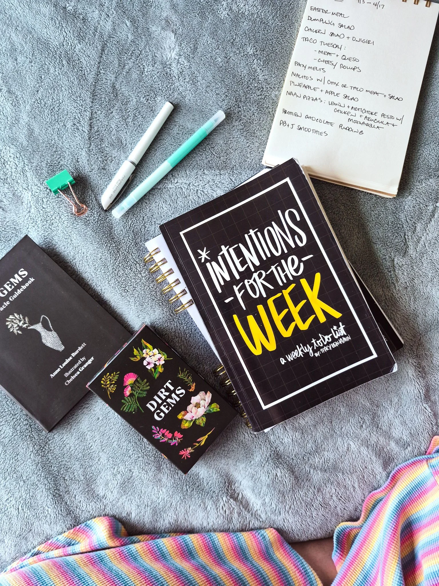 a cozy morning planner setup with a stack of planners and intention journals with a deck of botanical oracle cards nearby