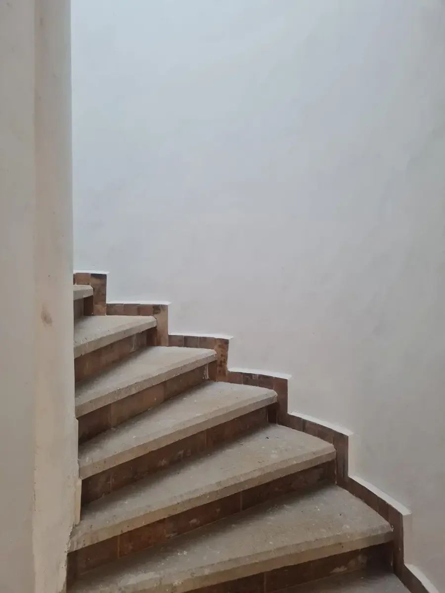 Escalera de ladrillos en construcción con pisos de concreto y paredes blancas