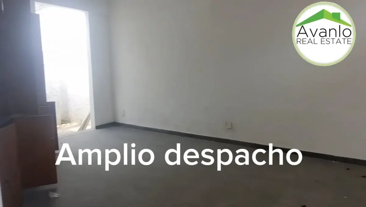 Sucursal inmobiliaria con un salón grande y vacío, con paredes blancas y puerta de acceso a un patio trasero.