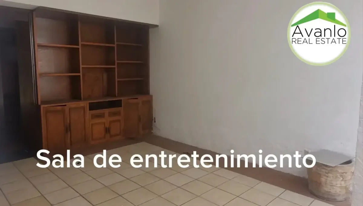 Sala de entretenimiento con estantería de madera en la pared y piso de baldosas.