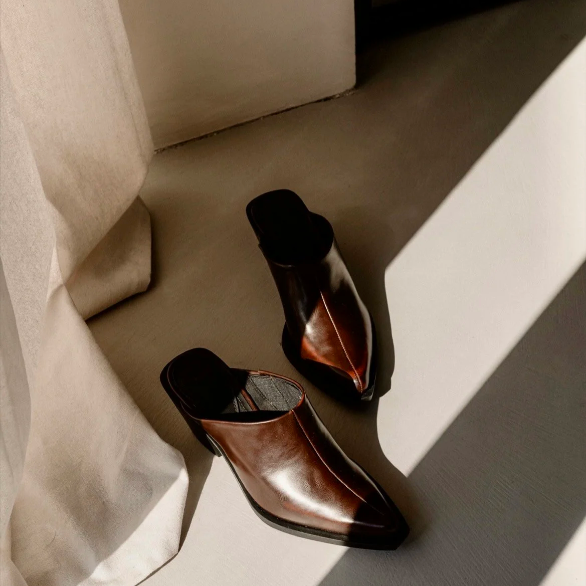 brown leather mule slides on a neutral background