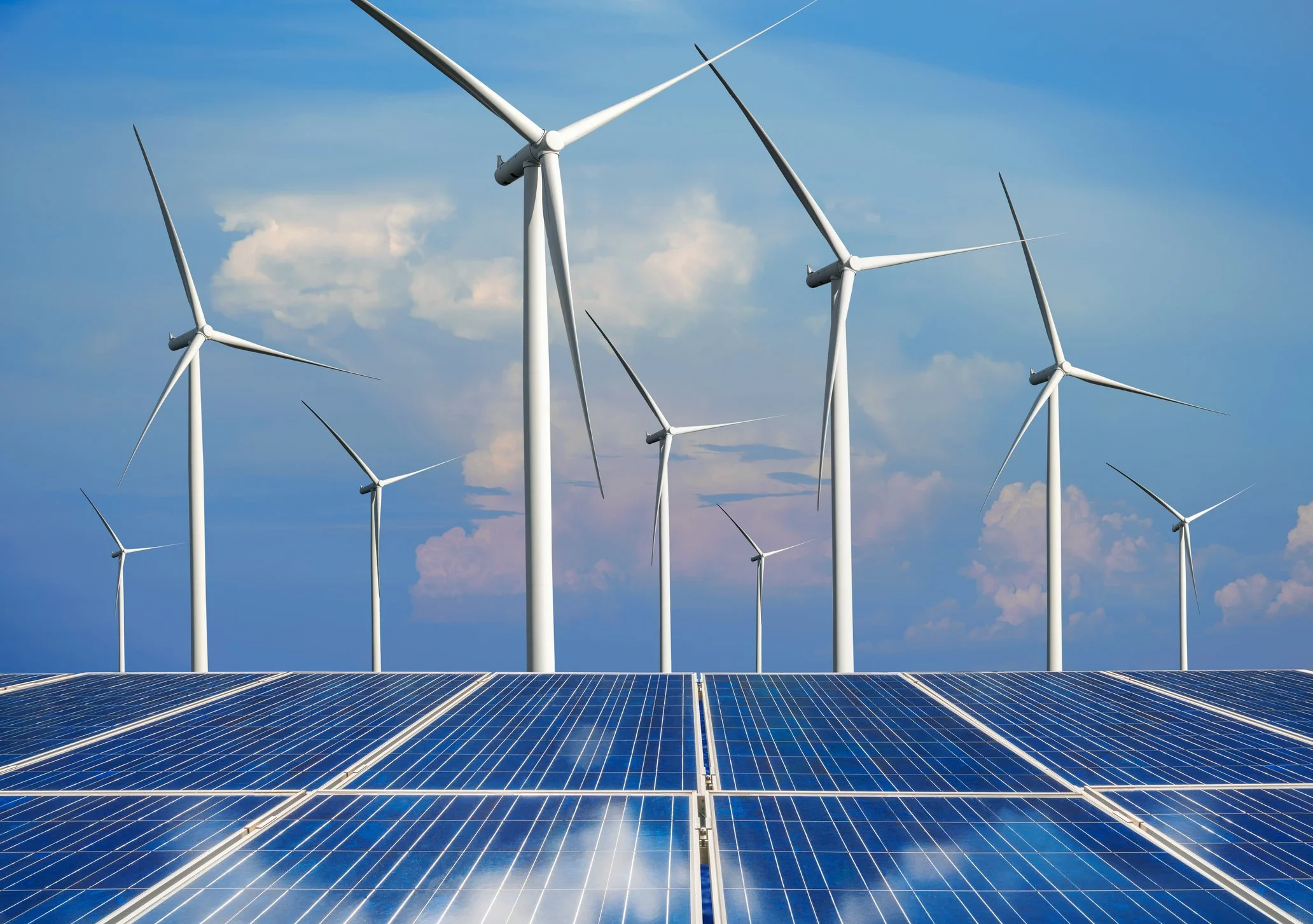 wind turbines standing behind a solar array