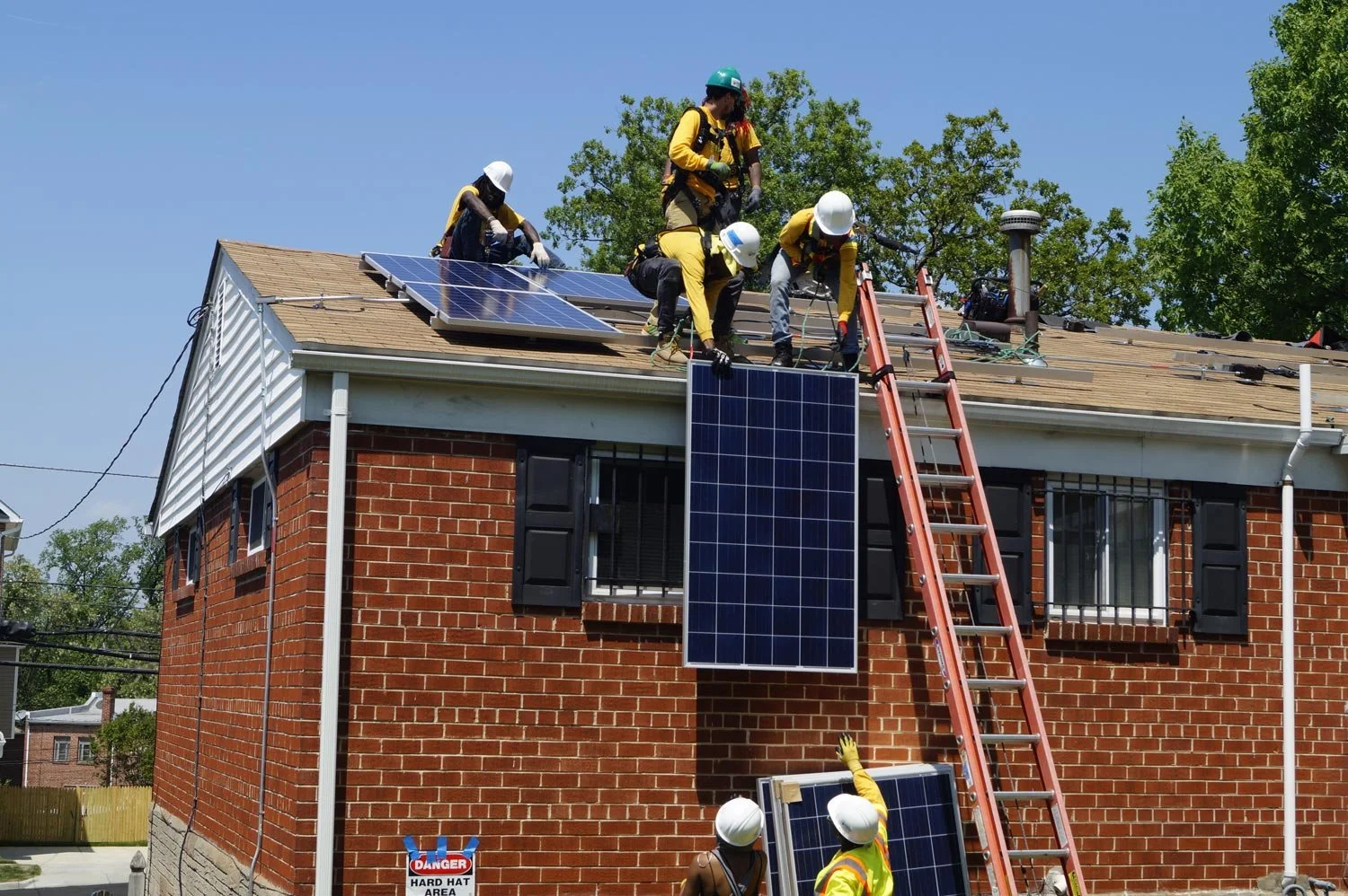 people installing solar panels on a roof of a brick building