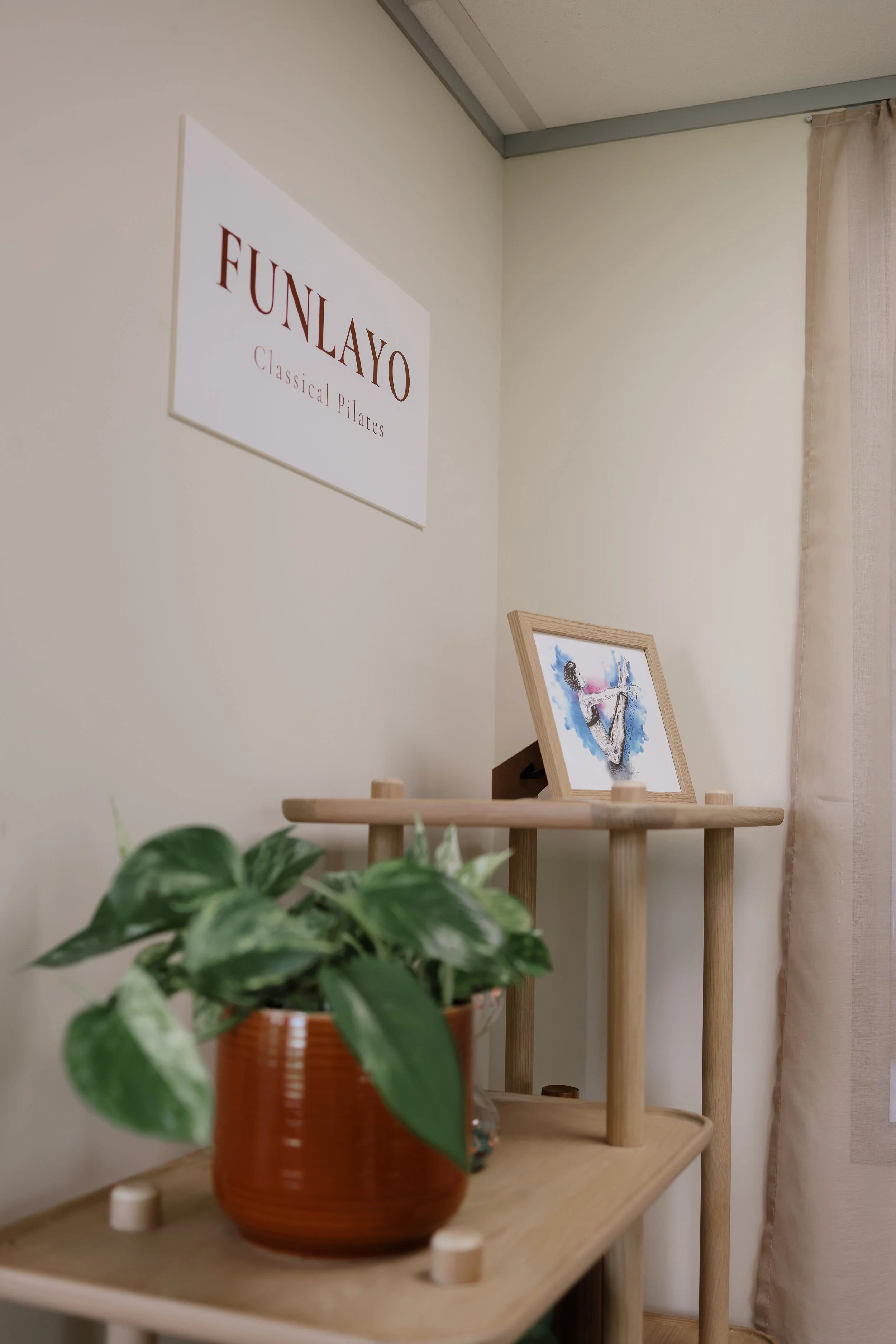 FUNLAYO Classical Pilates studio interior with plants, artwork and studio sign.