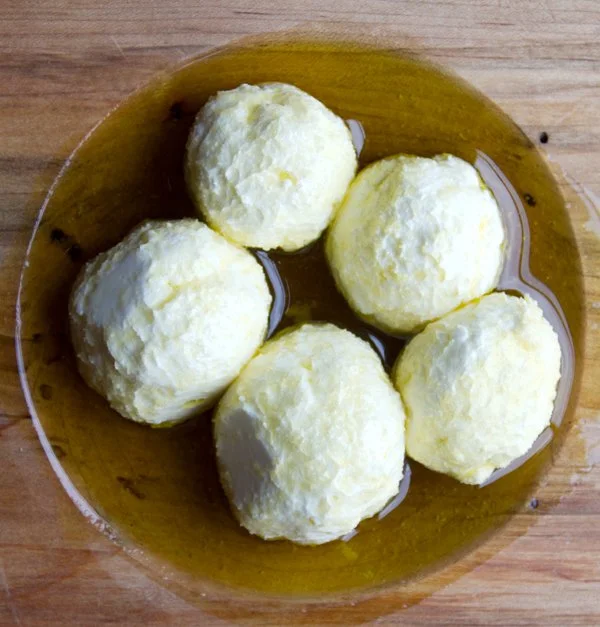 Modern backyard with a swimming pool, three lounge chairs, a patio with a house, trees, and landscaped garden with purple flowers.