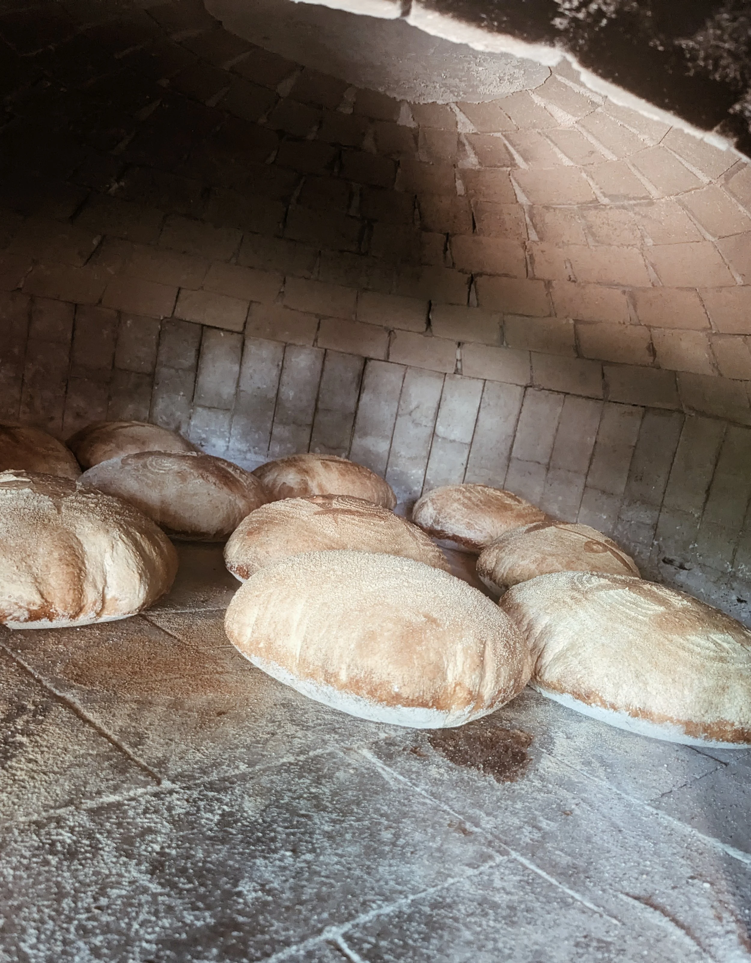 Loaves of bread baking inside a brick oven