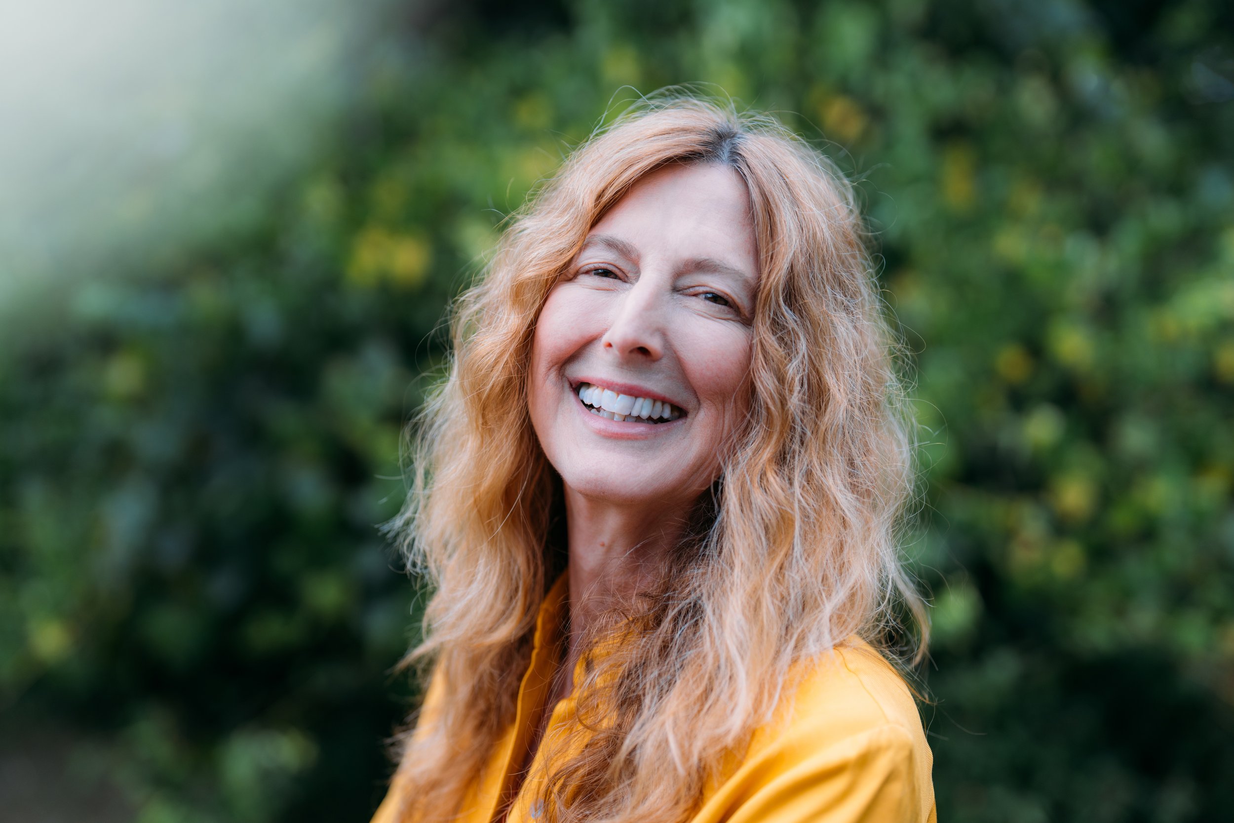 A portrait of Deanna Walker wearing a yellow shirt in nature.