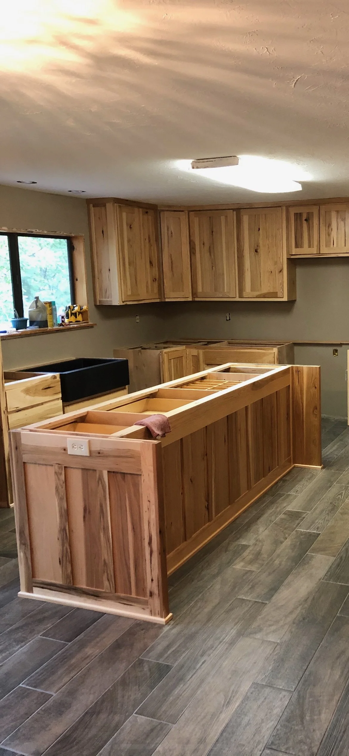 Kitchen under construction with wooden cabinets, a window, and a partially installed countertop.