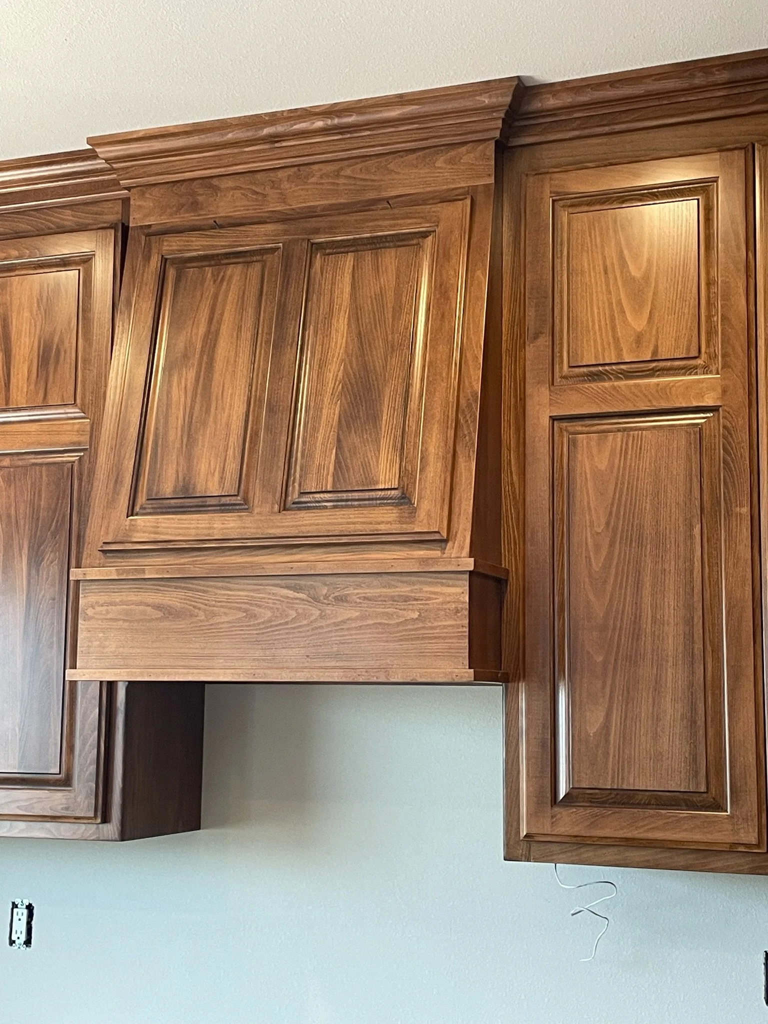 Wooden kitchen cabinets mounted on a white wall, with no hardware.