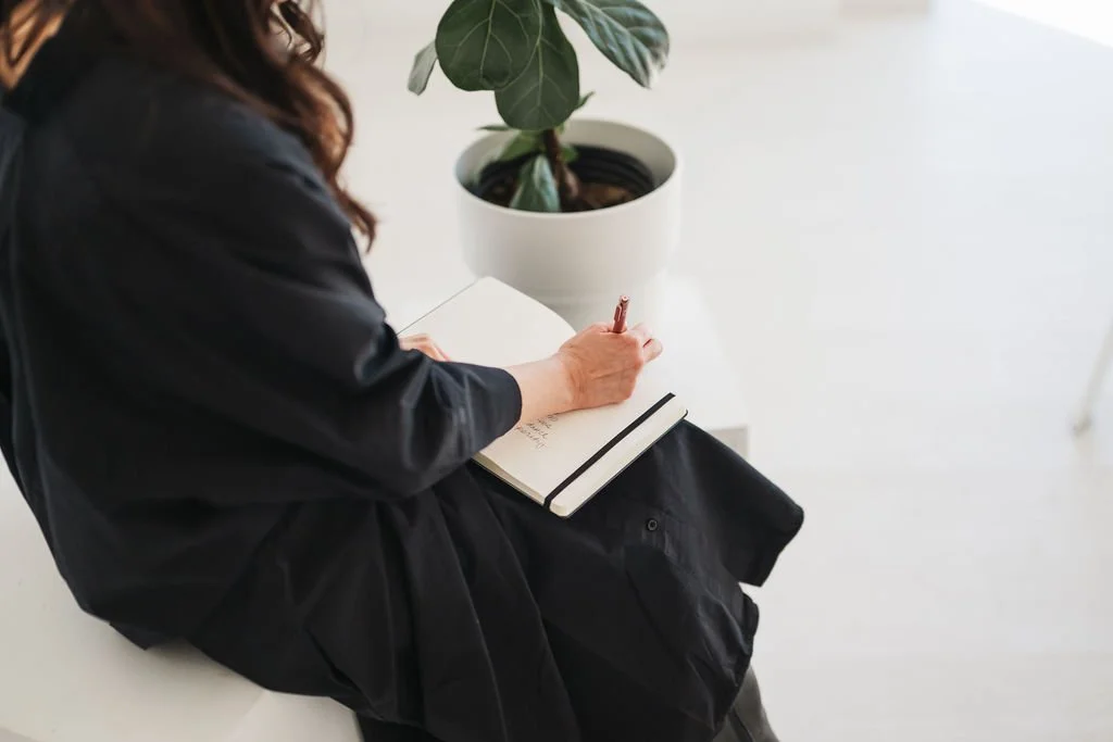 Photo of woman in black dress holding journal writing