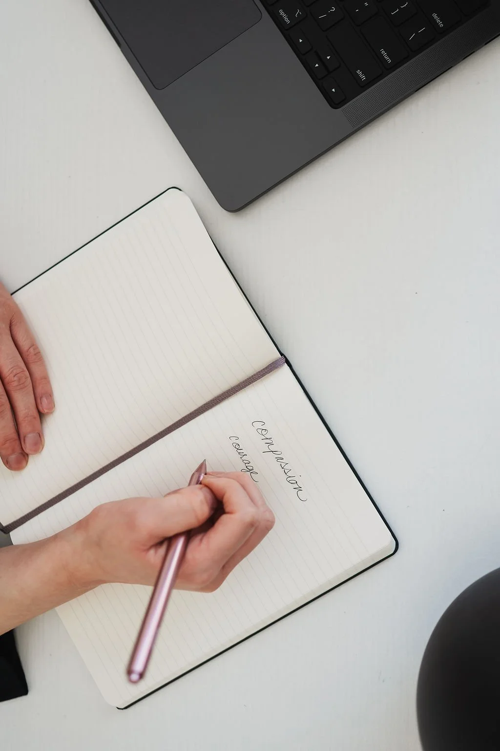 Photo of woman holding pink pen writing in journal