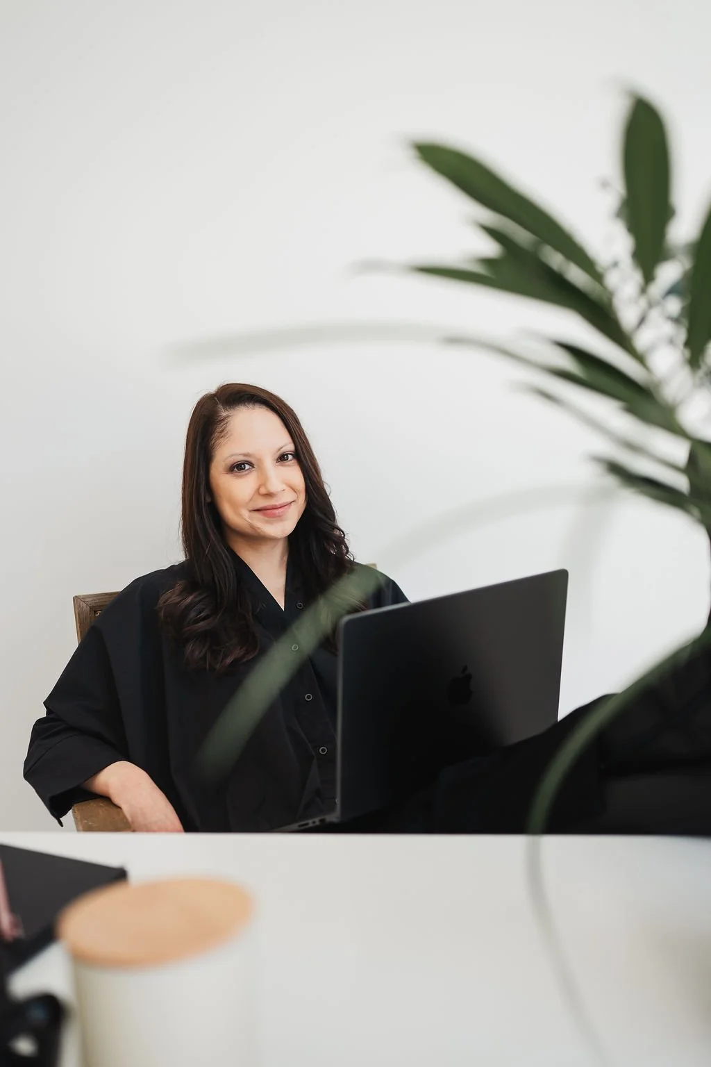 Image of woman in black dress with laptop sitting in chait