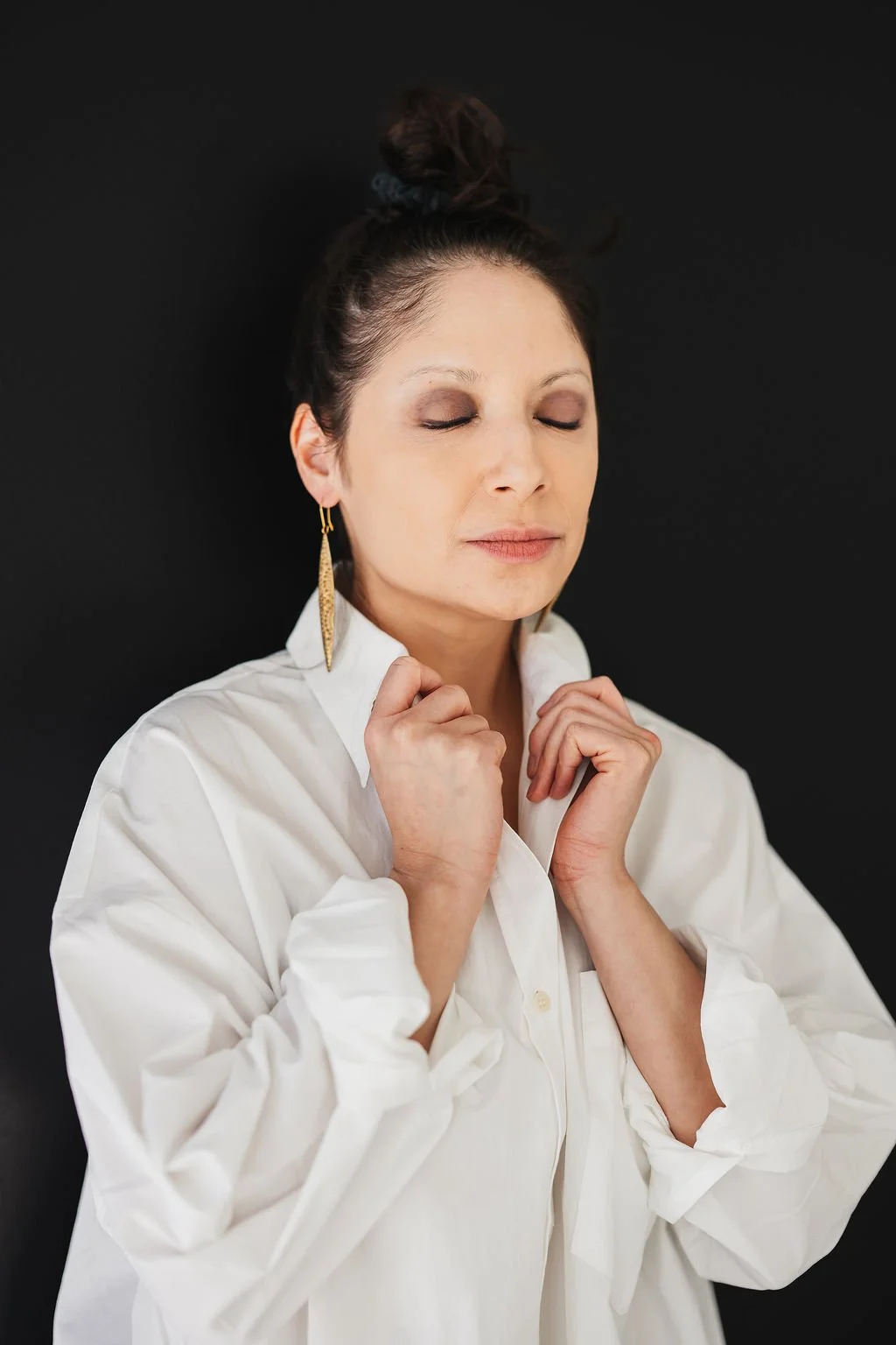 Photo of woman in white collared shirt closing her eyes and smiling