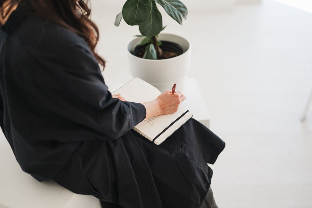 Woman in black dress holding journal and pen