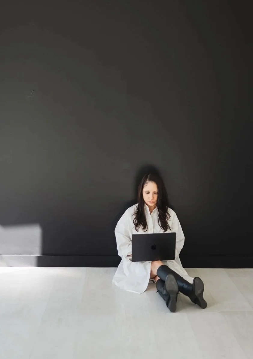 Photo of woman in white dress sitting on floor with laptop