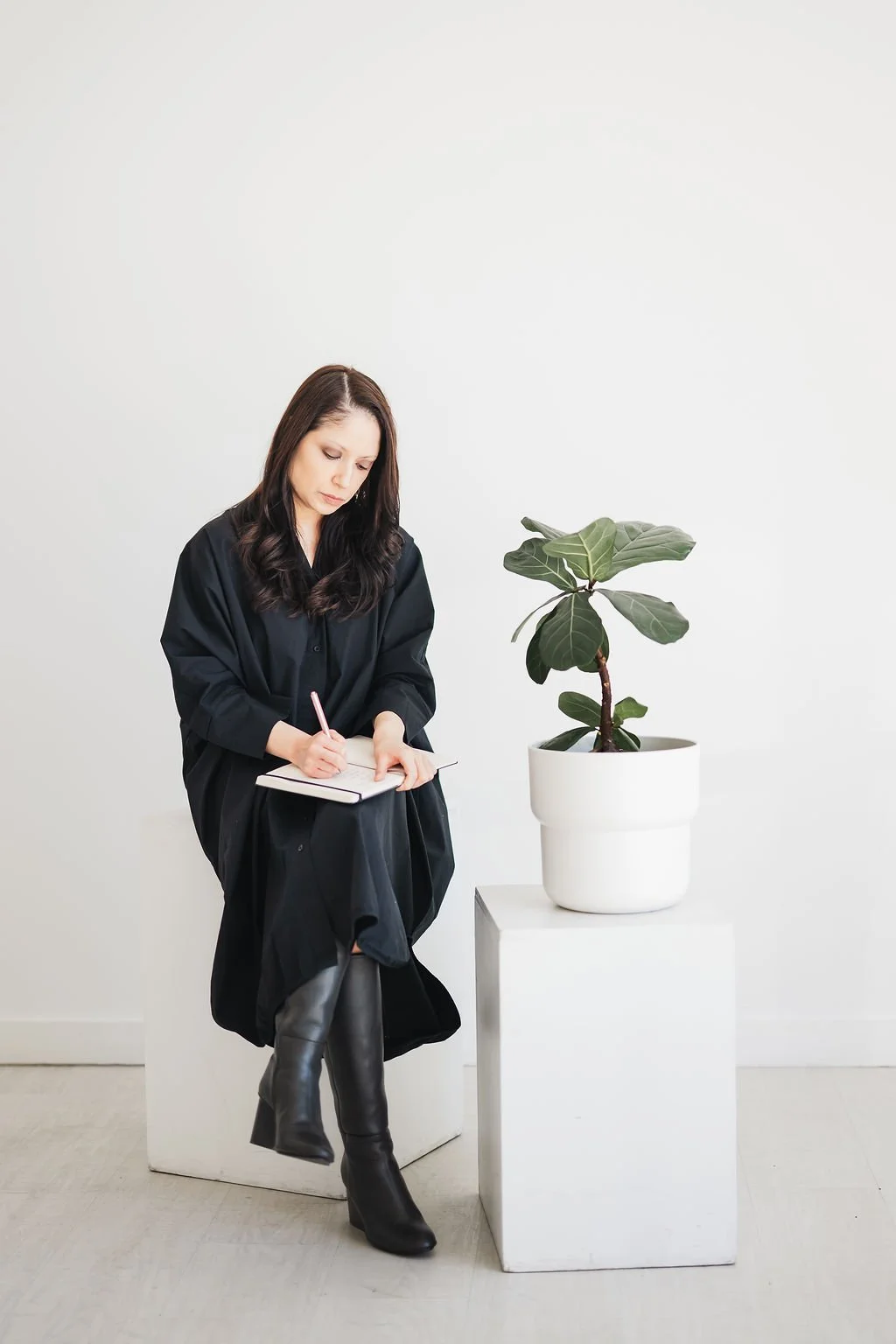 Image of woman in black dress journaling on her lap
