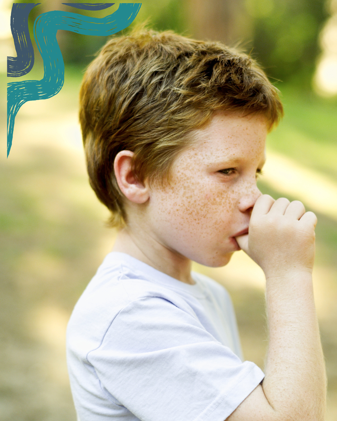 A young boy with red hair and freckles is outside, holding his hand to his nose, with a contemplative expression.