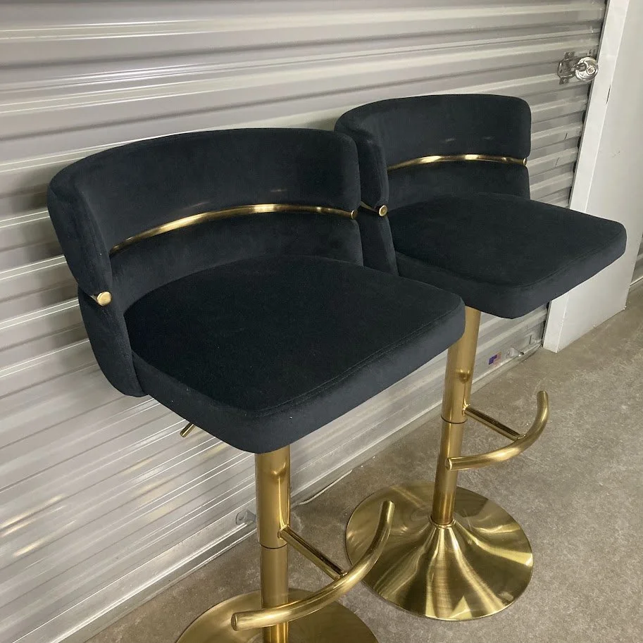 Angled view of LumiSource Cinch black velvet swivel barstools with gold base
