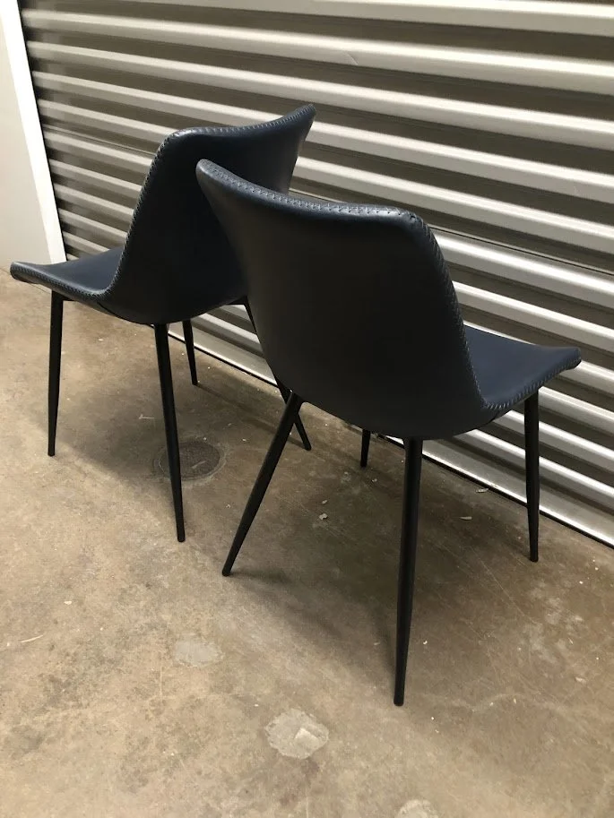 Side profile of navy blue faux leather dining chair with black legs
