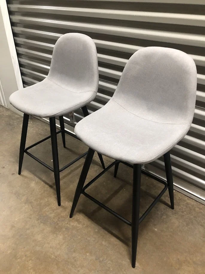 Angled view of LumiSource Pebble grey fabric counter stools with black metal frame