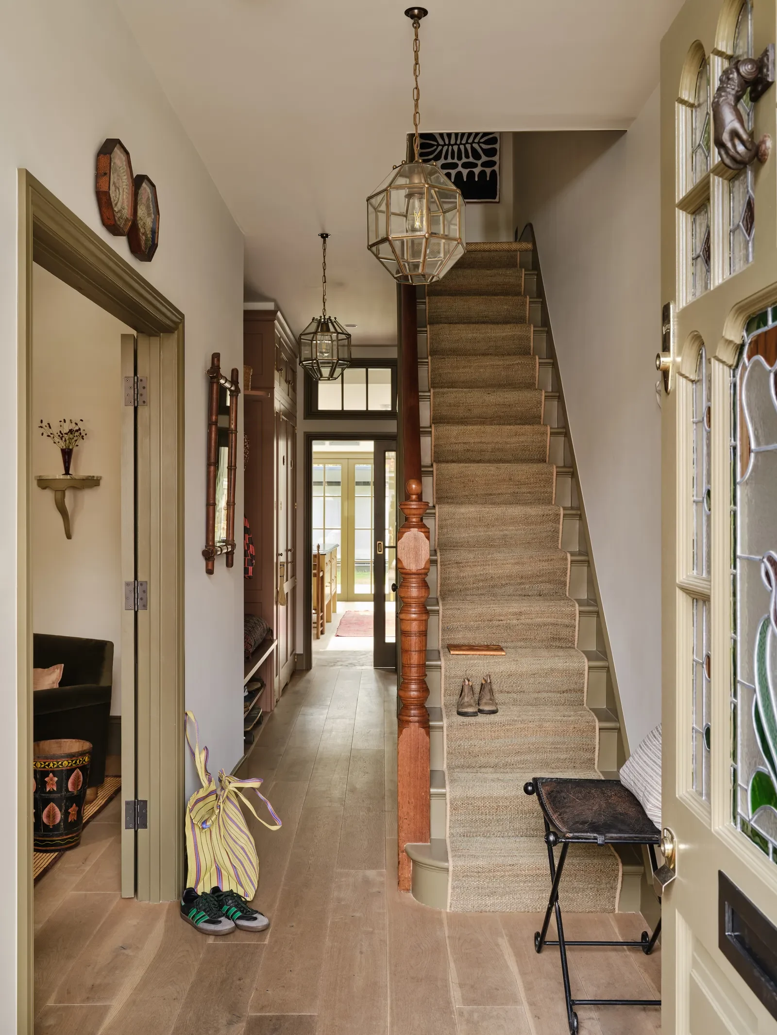 Entryway of a home with a staircase, hanging pendant lights, and front door with stained glass.