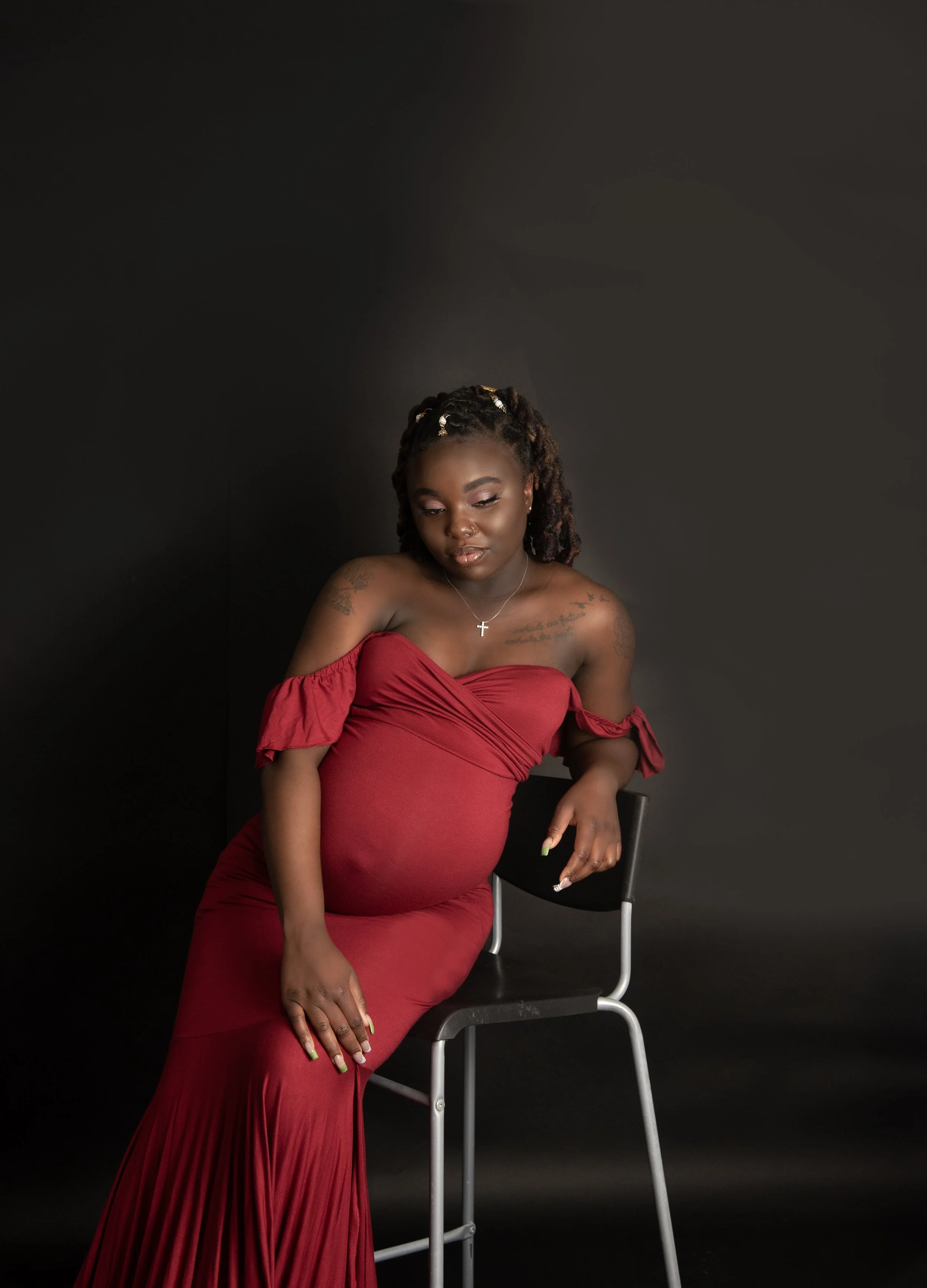 Expecting mama reclining in chair wearing red maternity gown