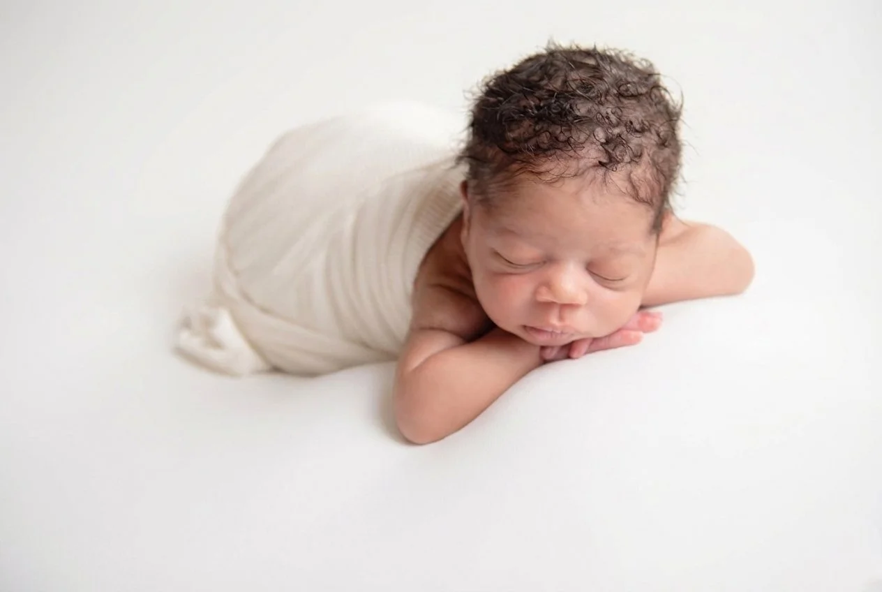 Newborn baby boy wrapped in white fabric on white background