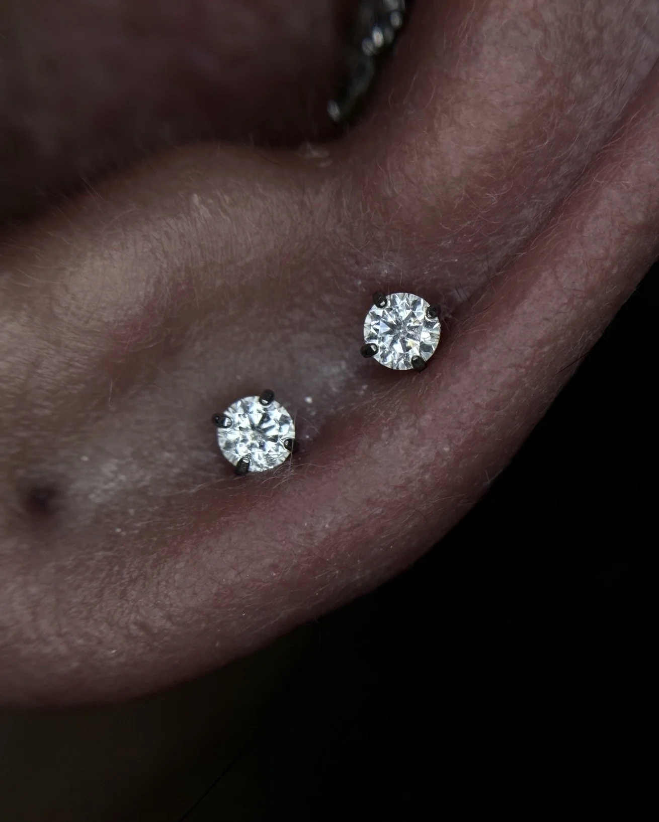 Close-up of a person's ear with two diamond stud earrings.