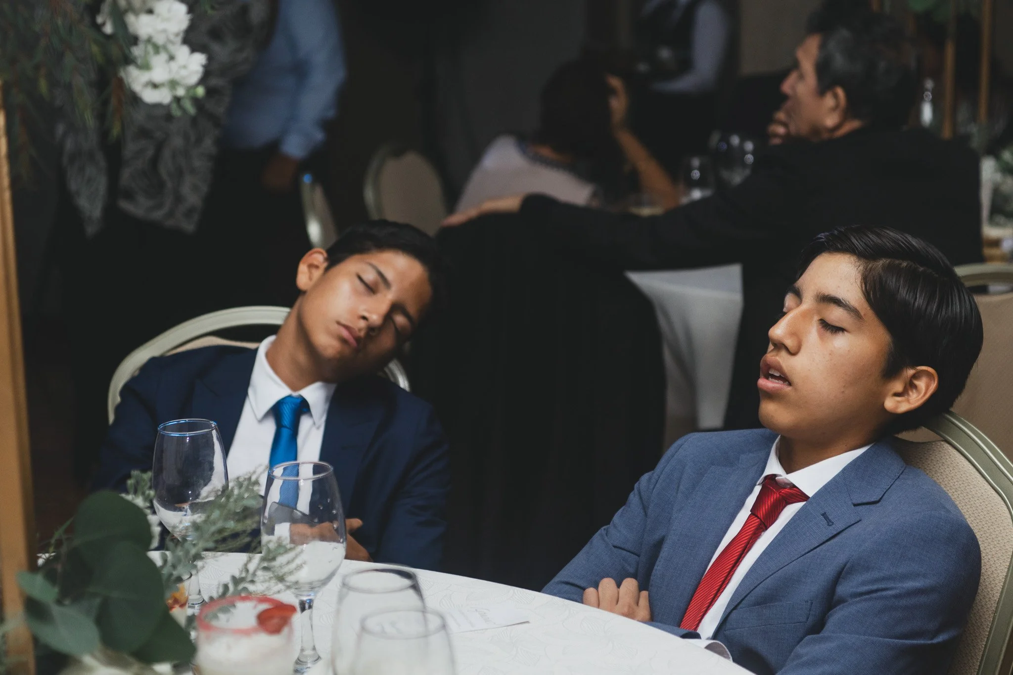 Jóvenes dormidos en una mesa en una comida o evento formal.