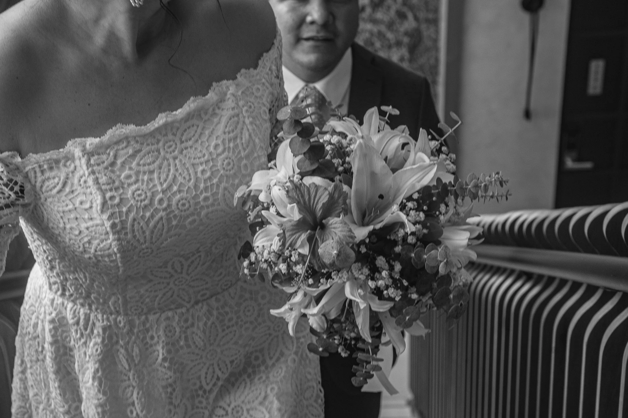 Mujer en vestido de encaje sosteniendo un ramo de flores en una ceremonia.