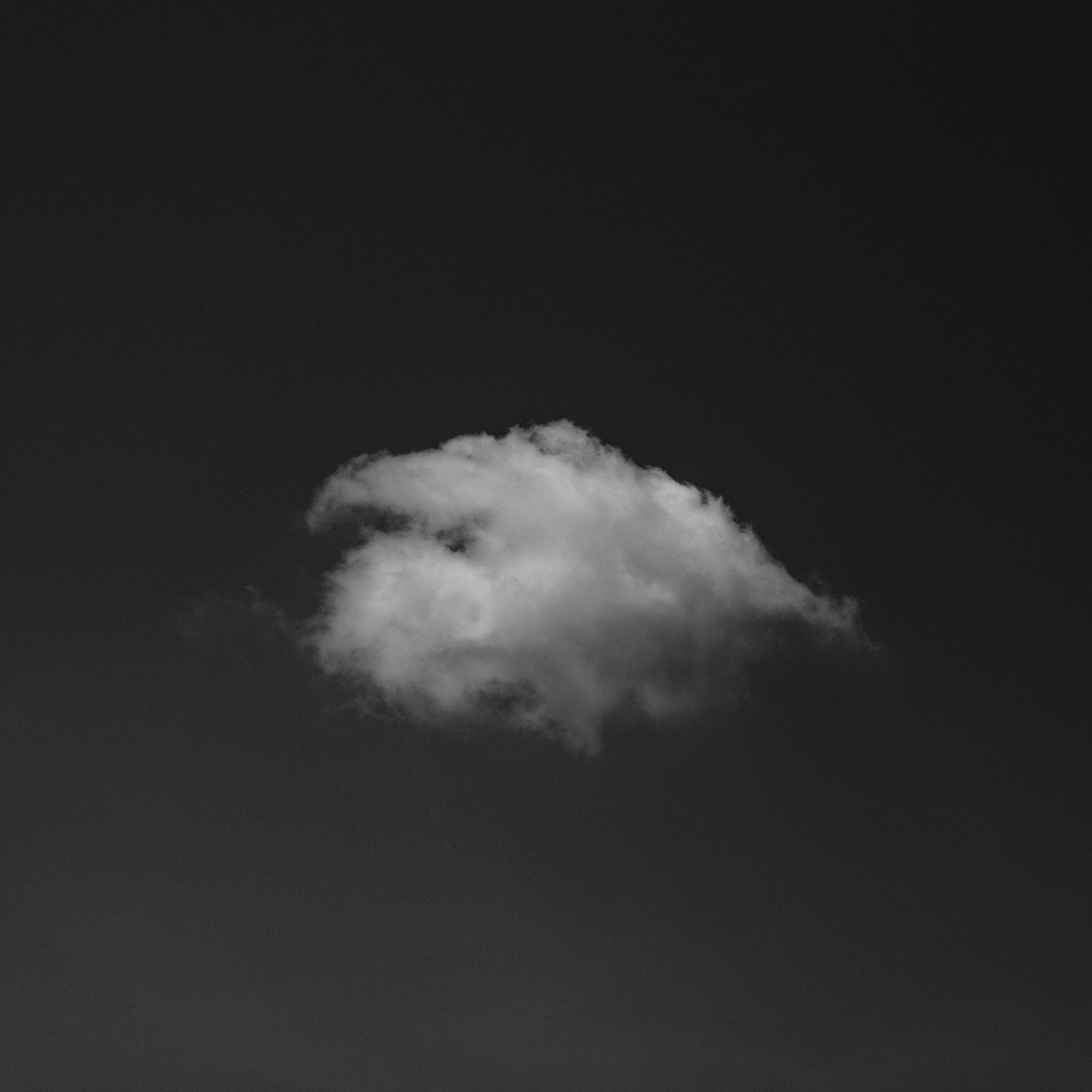 A single white cloud in the sky against a dark background.