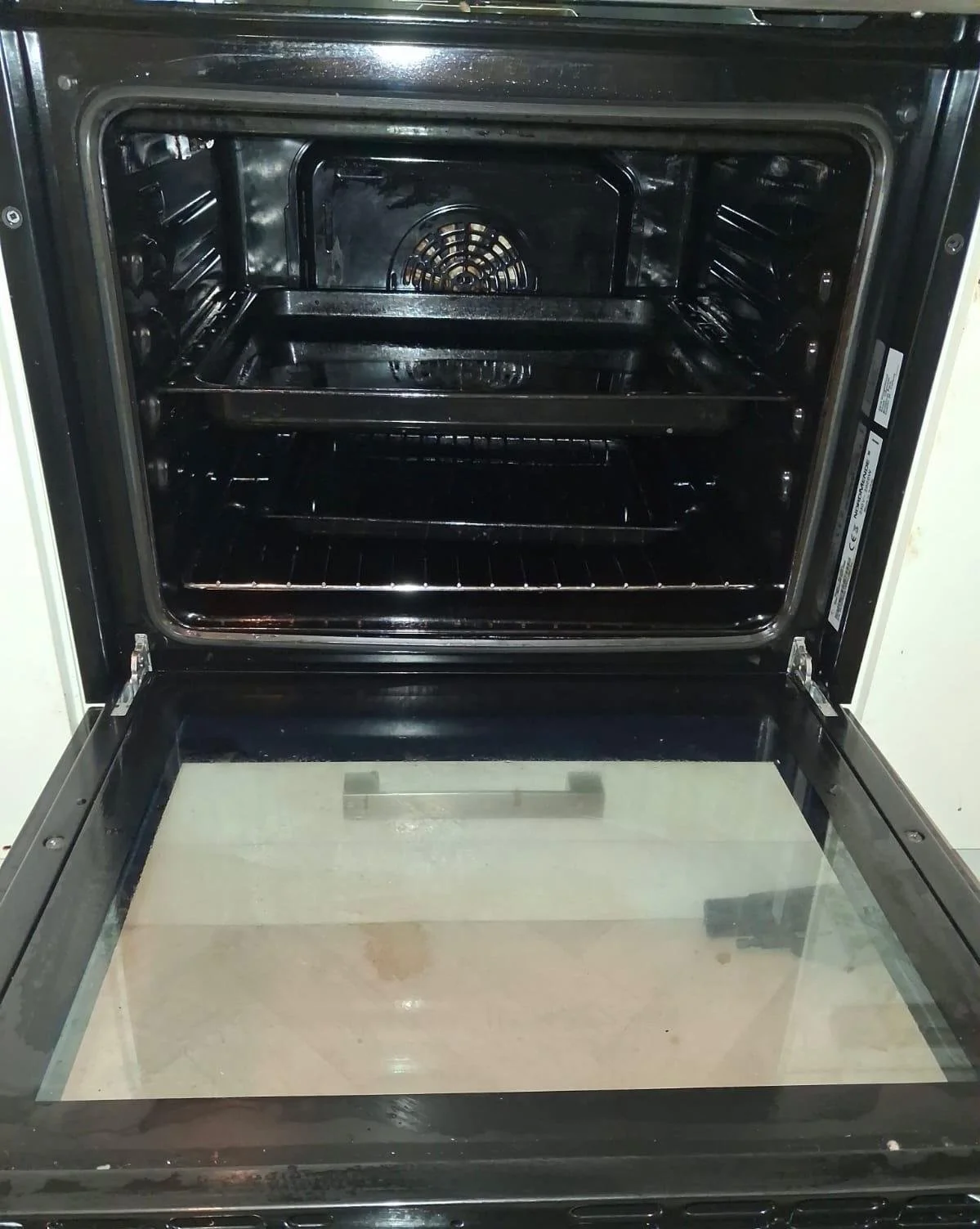 Empty black oven with glass door and interior racks, viewed from front.