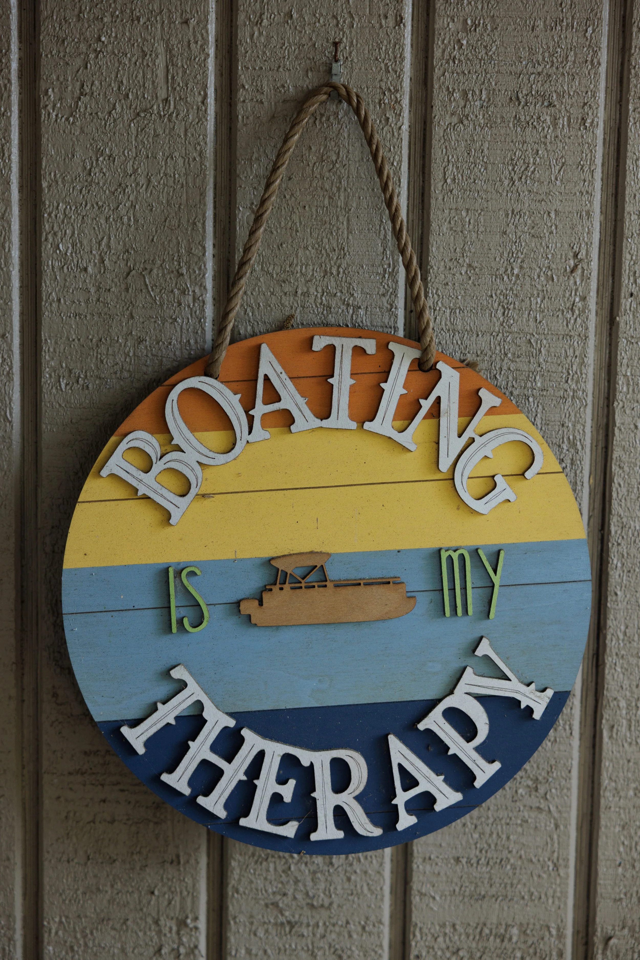 A colorful wooden sign with the words "Beach Vibes" in white 3D letters, featuring a boat illustration, hanging on a textured wall.