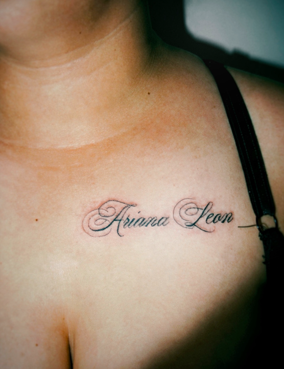 Fine line script text of a woman's name on a chest