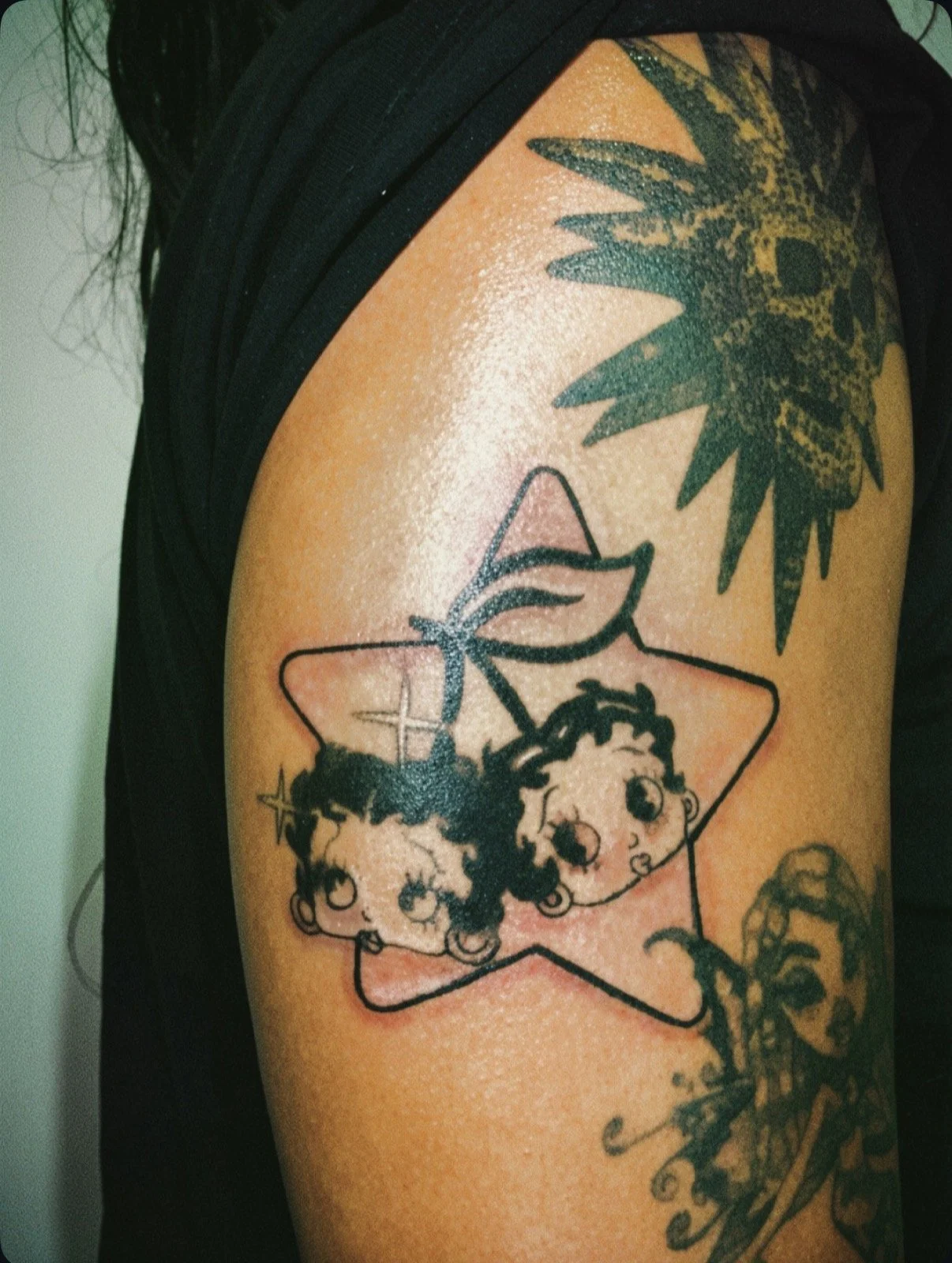 a black and grey betty boop tattoo in the shape of cherries inside of a star.