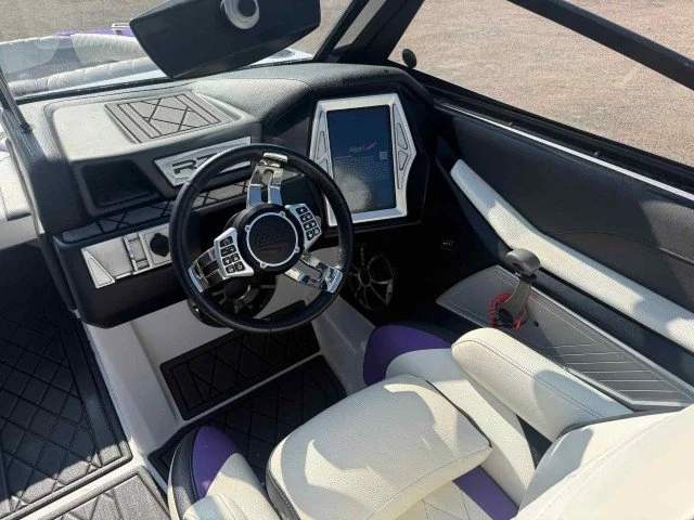 Interior of a race car cockpit with steering wheel, digital display, and racing seat