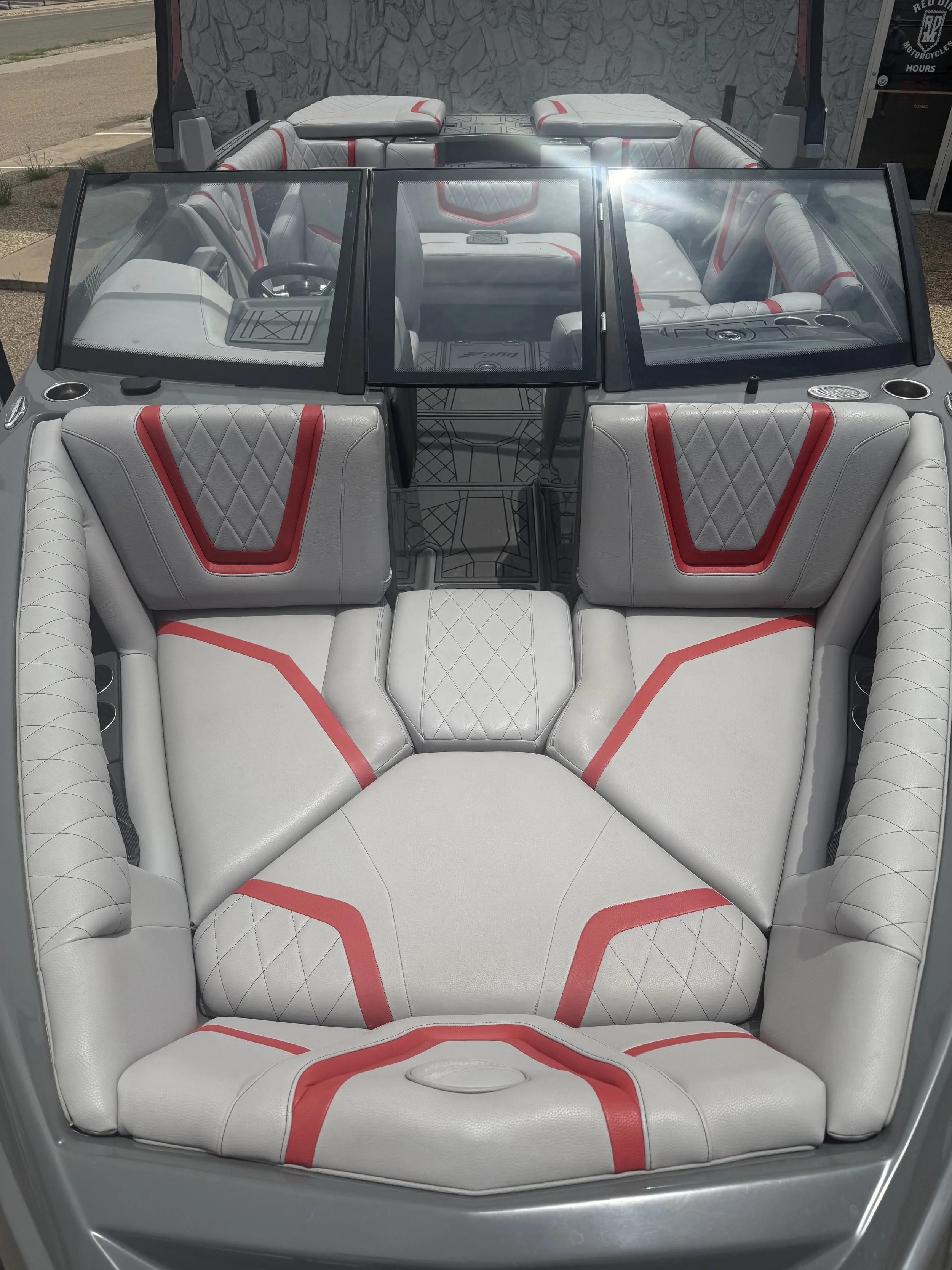 The image shows the interior of a white boat with red and gray accents, including seating and a windshield.