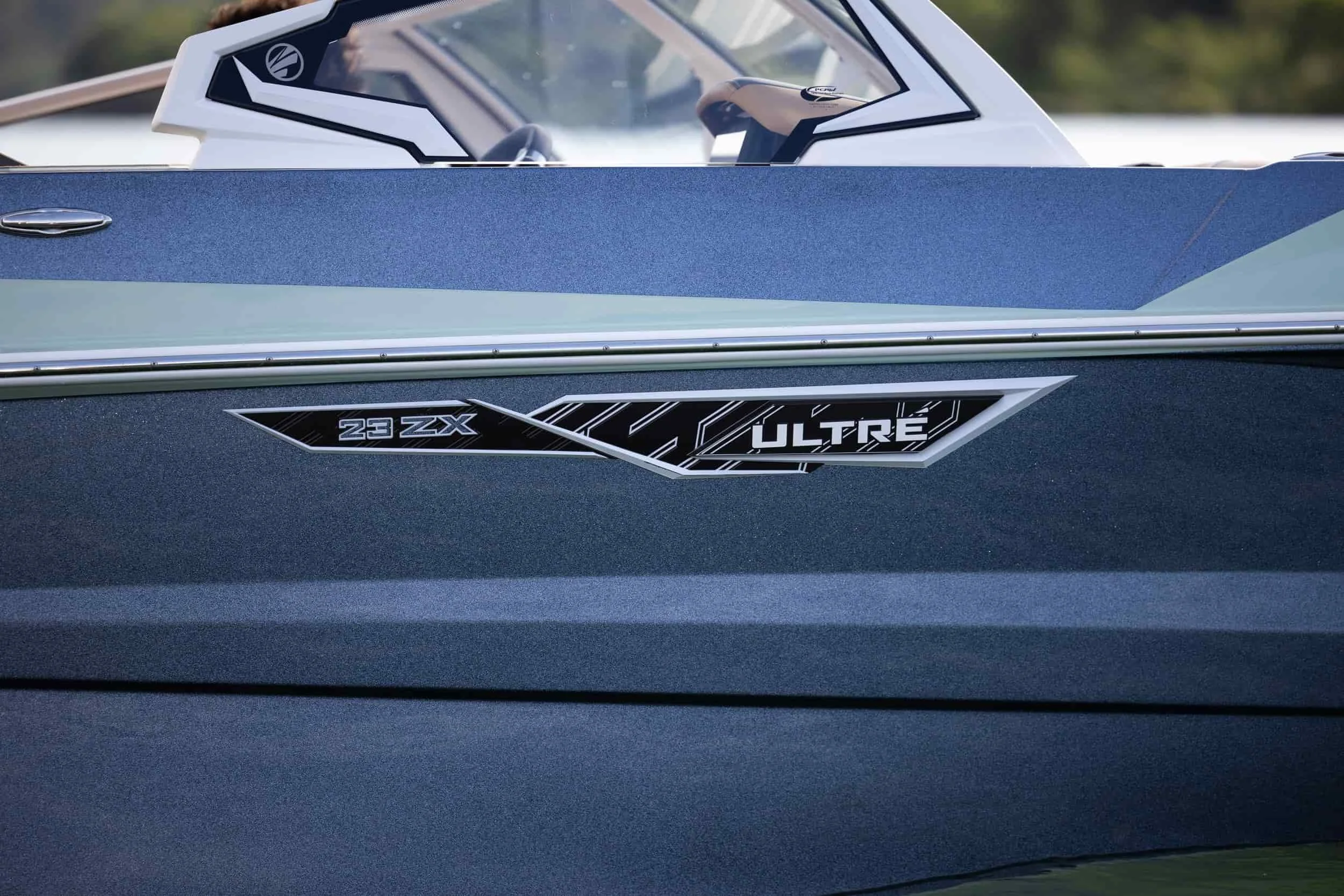 Close-up of a blue boats side with 23 ZX and ULTRE labels visible near the water.