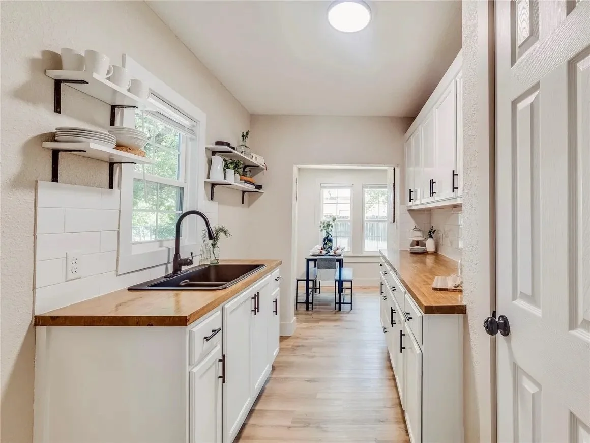A white kitchen with white cabinets and wood countertops