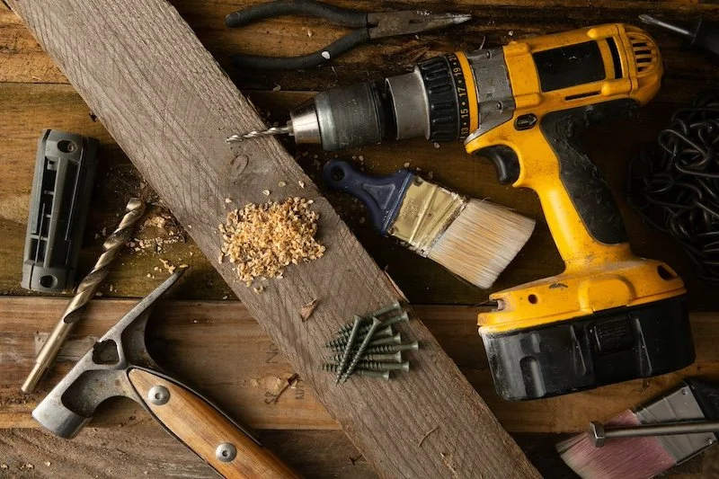 Yellow power drill, hammer, and tools arranged with screws and wood shavings—perfect for your next remodel project.