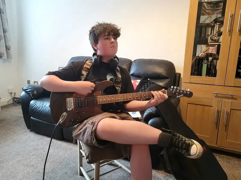 Young student learning a chord during a fun group guitar lesson at PowerUp Guitar Academy in Winsford