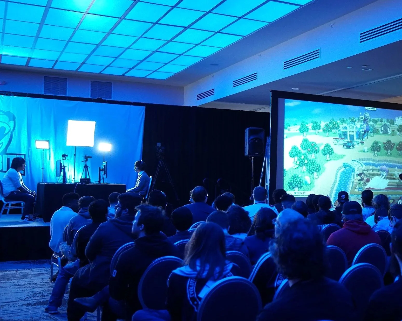 Corporate presentation with projector screen and seated attendees at an event venue.