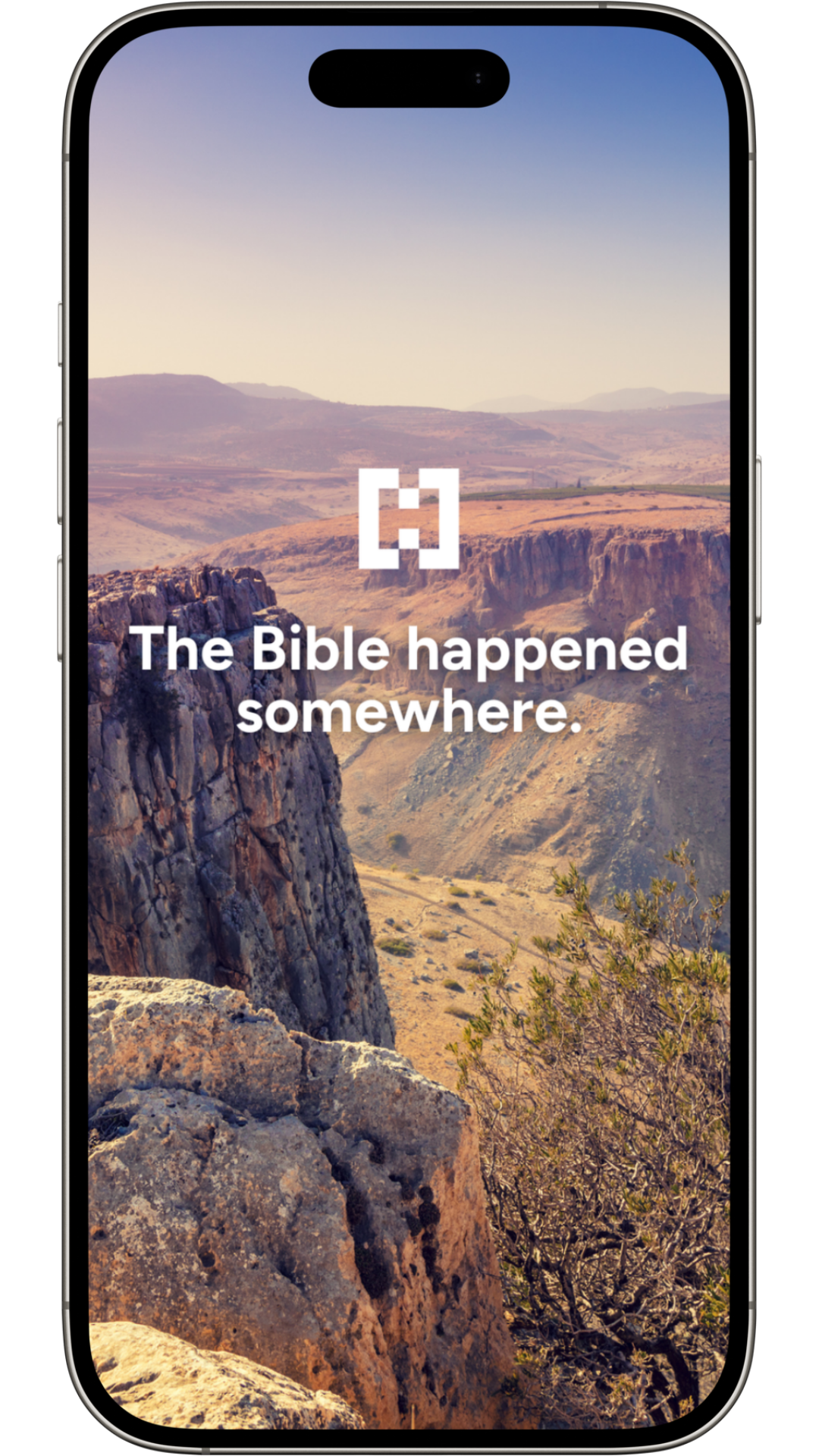 A smartphone screen showing a landscape background with rocks and desert terrain, with the text 'The Bible happened somewhere.'