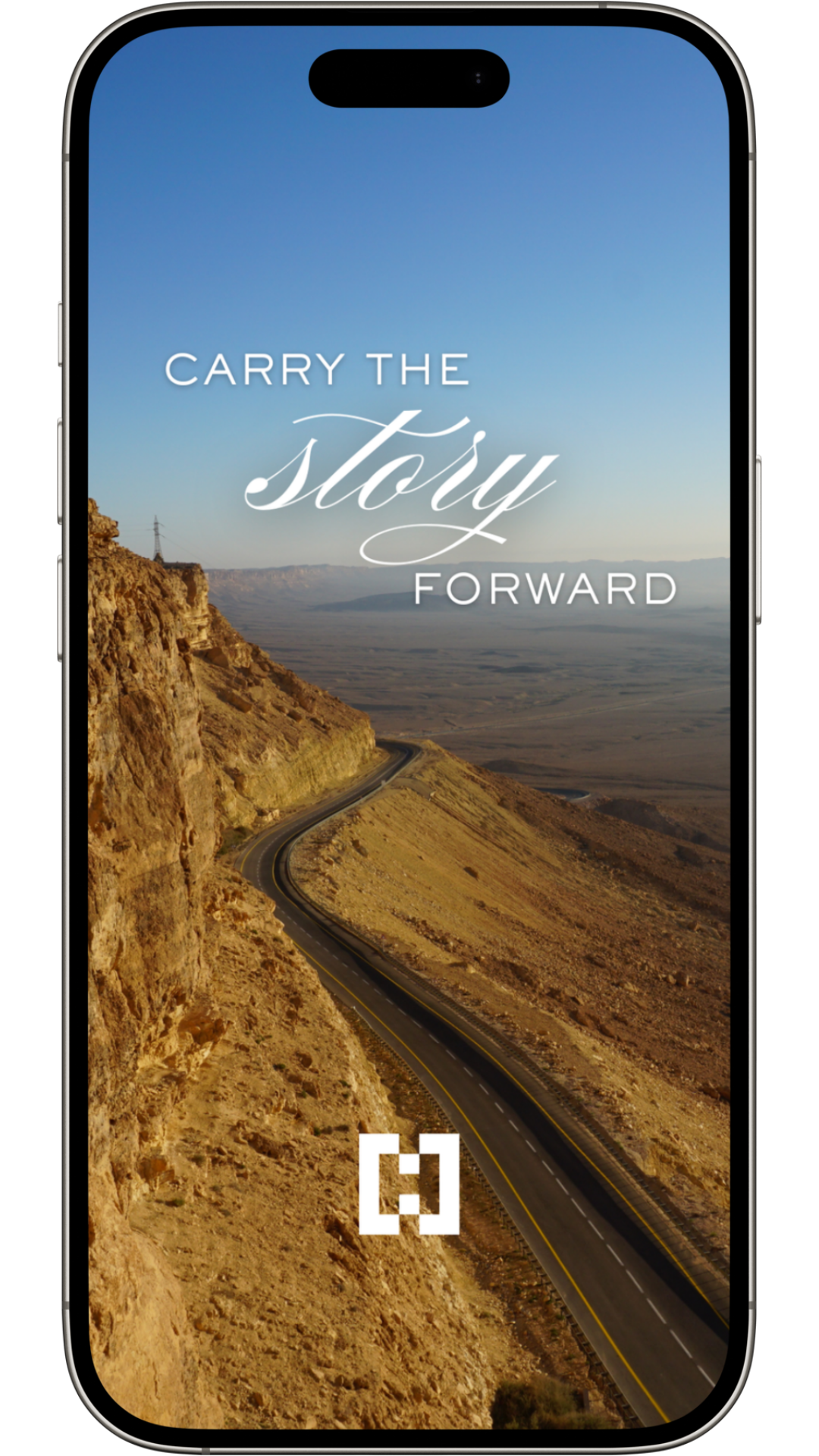 Smartphone displaying an inspirational message over a landscape of winding mountain road and desert terrain with clear blue sky.