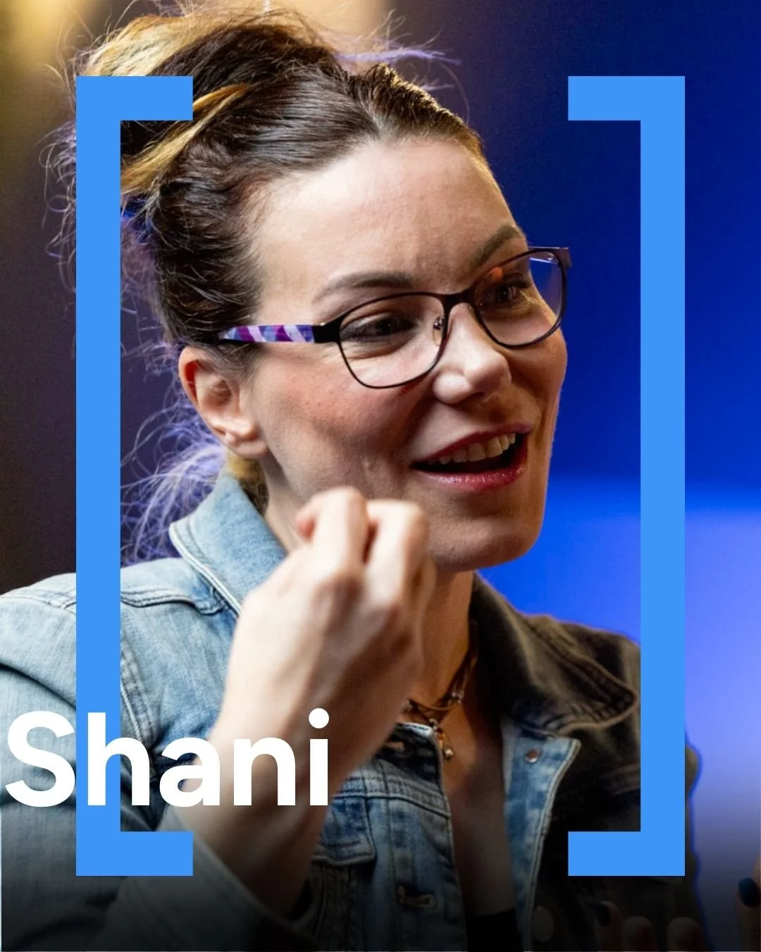 A woman with glasses, wearing a denim jacket, smiling and talking, with her hand near her face, and the name "Shani" displayed at the bottom.