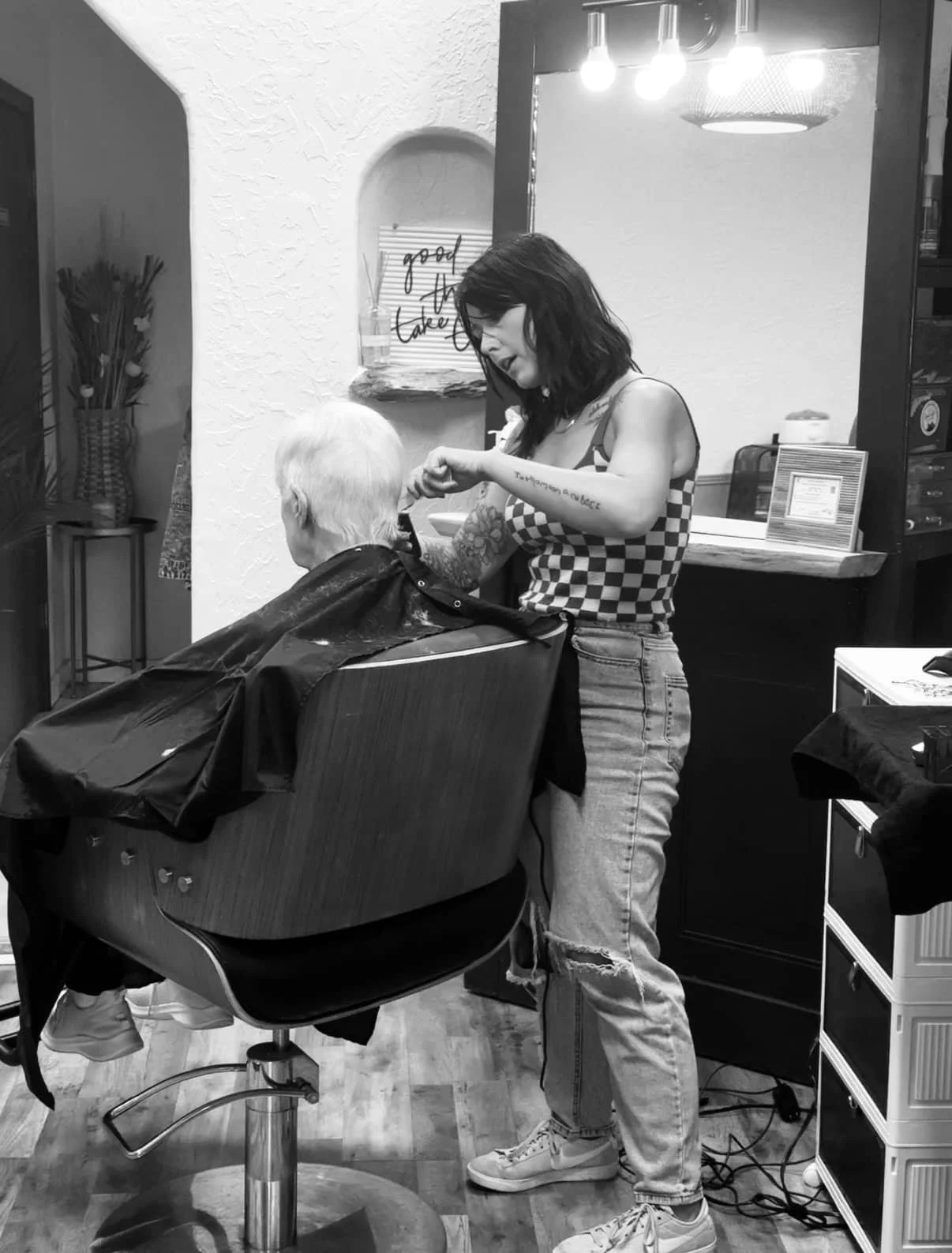 A woman giving a haircut to an elderly person in a salon, with salon tools and furniture visible.