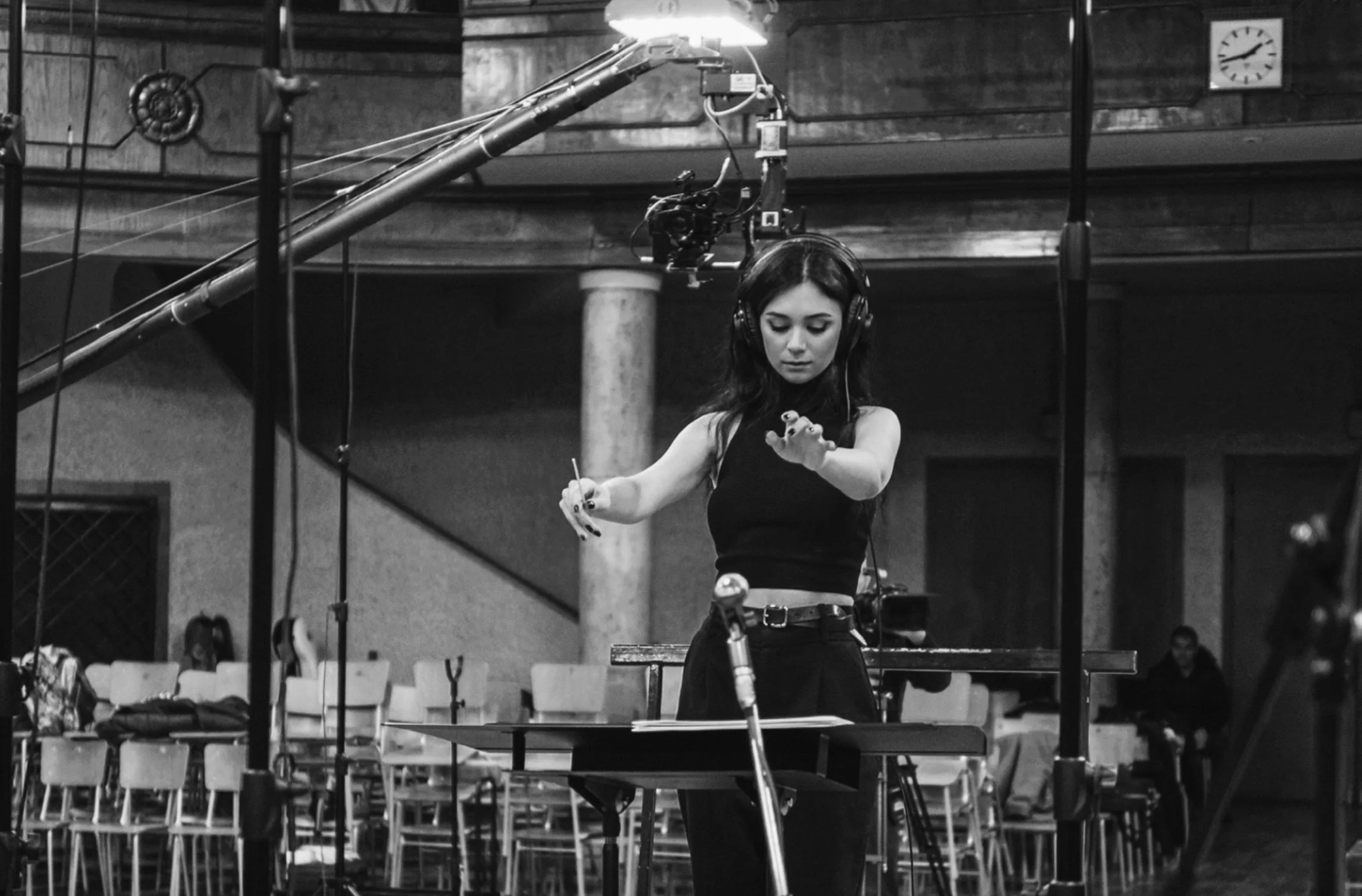 A woman wearing headphones is operating audio equipment a concert or event setting with chairs in the background.
